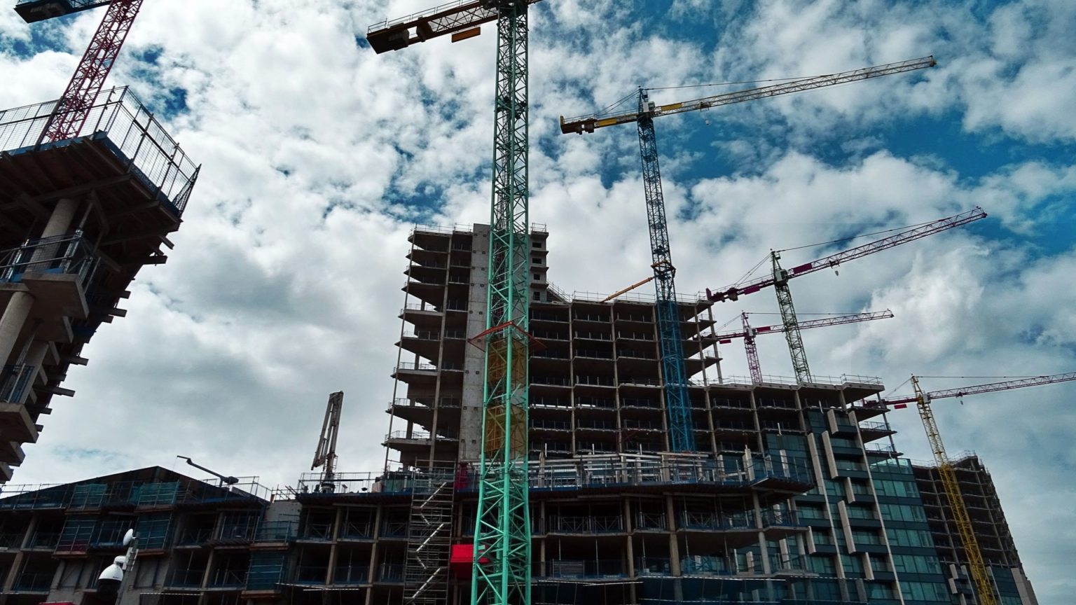 Zahlreiche Kräne arbeiten auf einer Baustelle an einer Immobilie